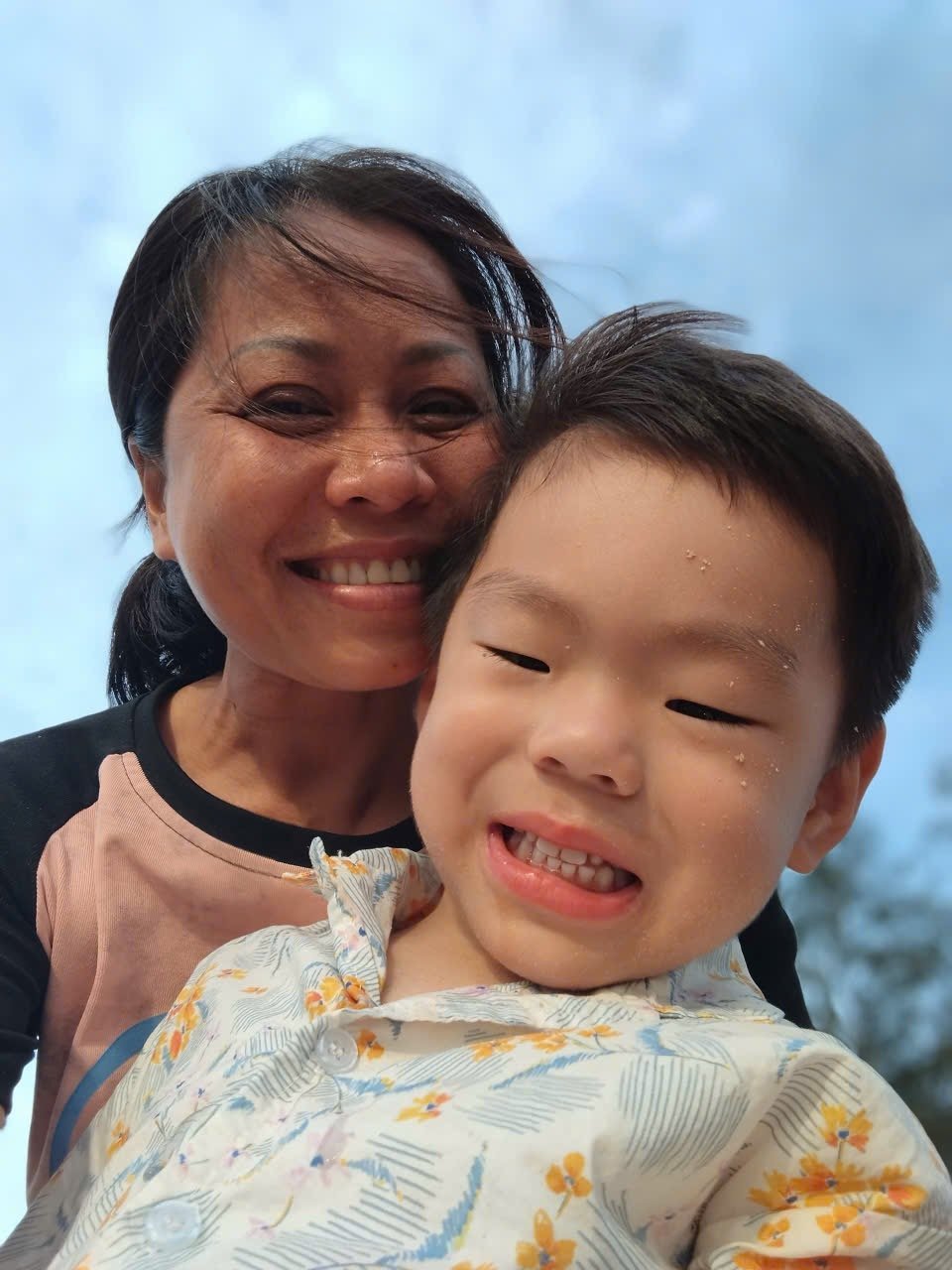 Moon Moon babysitter smiling outdoors with a happy child under a blue sky